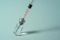 Syringe needle pierces the cap of medical vial on blue background