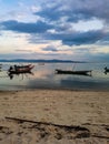 Long tail boat ship sea ocean gulf water mirroring beach sand clouds sky warm light sunset sundown thailand koh samui Royalty Free Stock Photo