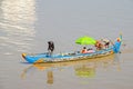 Long-tail Mekong boat with a Cambodian family manoevring it on to the coast of the Mekong river