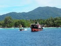 A long tailed boat running next to big vessel