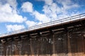 Long and tall industrial concrete wall with rusted metal catwalk before blue sky with clouds