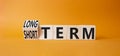 Long term vs Short Term symbol. Turned wooden cubes with words Long term and Short Term. Beautiful orange background. Business