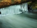 Long thin icicles are hanging on fallen trunk. Royalty Free Stock Photo