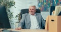 Long-time experienced boss of company in old age with gray hair retires promoted on desk there is box with packed things