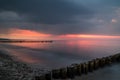 Colorful sunset at a beach of the baltic sea with groins in the forground