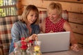 Long time friends senior women laugh together while lookiing at lap top, at home. Two Senior Women Using Laptop at home