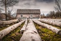 Long tree logs in front of rustic, abandoned and weathered house in countryside