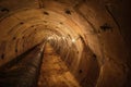 Long underground round concrete tunnel with a pipe, lit by incandescent lamps. Underground tunnel of a heating main or a water Royalty Free Stock Photo