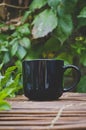 A long view of a blank black coffee mug on the bamboo cafe table edge