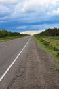 The long view of a highway with a storm brewing in the distance