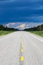 The long view of a highway with a storm brewing in the distance