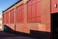 Long view of old red brick commercial industrial building with windows shuttered, loading dock door Royalty Free Stock Photo