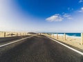 Long way road for travel car transportation concept with desert and beach on the side - sea water and blue clear beautiful sky in Royalty Free Stock Photo