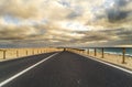 Long way road for travel car transportation concept with desert and beach on the side - sea water and cloudy beautiful sky in Royalty Free Stock Photo