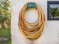 Long weathered garden hose hanging on a white wall during daytime