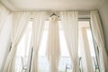 Long white dress of the bride with a lace corset on a black hanger on the ceiling on the cornice against the background Royalty Free Stock Photo