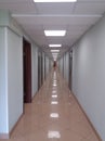 A long white hall with dark wood doors and a mirror-bright floor