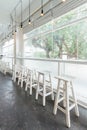 Long white wooden table and chairs with glass window and trees in background Royalty Free Stock Photo