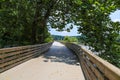 A long winding boardwalk along the river with a wooden rail along the sides with vast still river water, lush green trees Royalty Free Stock Photo