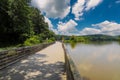 A long winding boardwalk along the river with a wooden rail along the sides with vast still river water, lush green trees Royalty Free Stock Photo