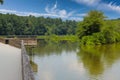 A long winding boardwalk along the river with a wooden rail along the sides with vast still river water, lush green trees Royalty Free Stock Photo