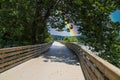 A long winding boardwalk along the river with a wooden rail along the sides with vast still river water, lush green trees Royalty Free Stock Photo