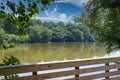 A long winding boardwalk along the river with a wooden rail along the sides with vast still river water, lush green trees Royalty Free Stock Photo