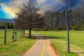 A long winding footpath in the park surrounded by lush green grass, bare winter trees and lush green trees with blue sky Royalty Free Stock Photo