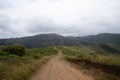 Long, winding hiking trail leading to mountains with two hikers marching into distance Royalty Free Stock Photo