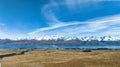 Long winding narrow gravel road across remote agricultural countryside towards the snow capped Southern alps mountain range Royalty Free Stock Photo