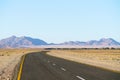 Long and winding road through desert landscape with distant hill Royalty Free Stock Photo