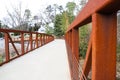 A long winding smooth paved rust colored bridge surrounded by lush green and autumn colored trees Royalty Free Stock Photo