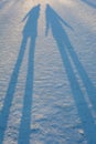 Long winter shadows in the snow of two people standing