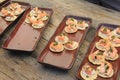 Long wood table with several brown trays offering appetizers of crackers topped with salmon