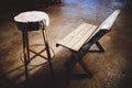 Long wooden benches and old wooden chairs in the room with the sunlight entering the window