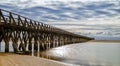 Long wooden boardwalk pier leads from one beach to another over a small ocean inlet Royalty Free Stock Photo