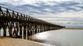 Long wooden boardwalk pier leads from one beach to another over a small ocean inlet Royalty Free Stock Photo