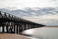 Long wooden boardwalk pier leads from one beach to another over a small ocean inlet Royalty Free Stock Photo