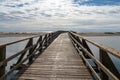Long wooden boardwalk pier leads from one beach to another over a small ocean inlet Royalty Free Stock Photo