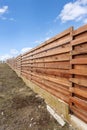 Long wooden cedar fence against blue sky. Royalty Free Stock Photo