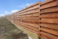 Long wooden cedar fence against blue sky. Royalty Free Stock Photo