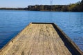 A long wooden dock on the lake with vast blue lake water with lush green and autumn colored trees and plants at Lake Horton Park Royalty Free Stock Photo