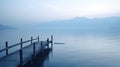 a long wooden dock in the middle of a lake with mountains in the background Royalty Free Stock Photo