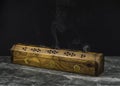A long wooden incense burner holder on a grey stone tile base with black background and copy space Royalty Free Stock Photo