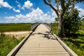 Long wooden path with a fence in the middle of green fields with trees in James Island County Park