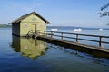 pier and boat houses on lake Ammersee with sailing boats and Alps in background in Bavarian village Schondorf (Germany) Royalty Free Stock Photo