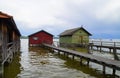 pier and boat houses on lake Ammersee with sailing boats and Alps in background in Bavarian village Schondorf (Germany) Royalty Free Stock Photo