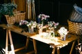 Long wooden table with different bouquetes of beautiful flowers. Pleasant smelling roses standing in glasses. Empty wooden backets