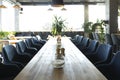 Long wooden table with soft chairs in cozy cafe Royalty Free Stock Photo