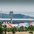 Long zoom view of airplanes on tarmac and iconic roof of Bajaras Airport in Madrid, Spain